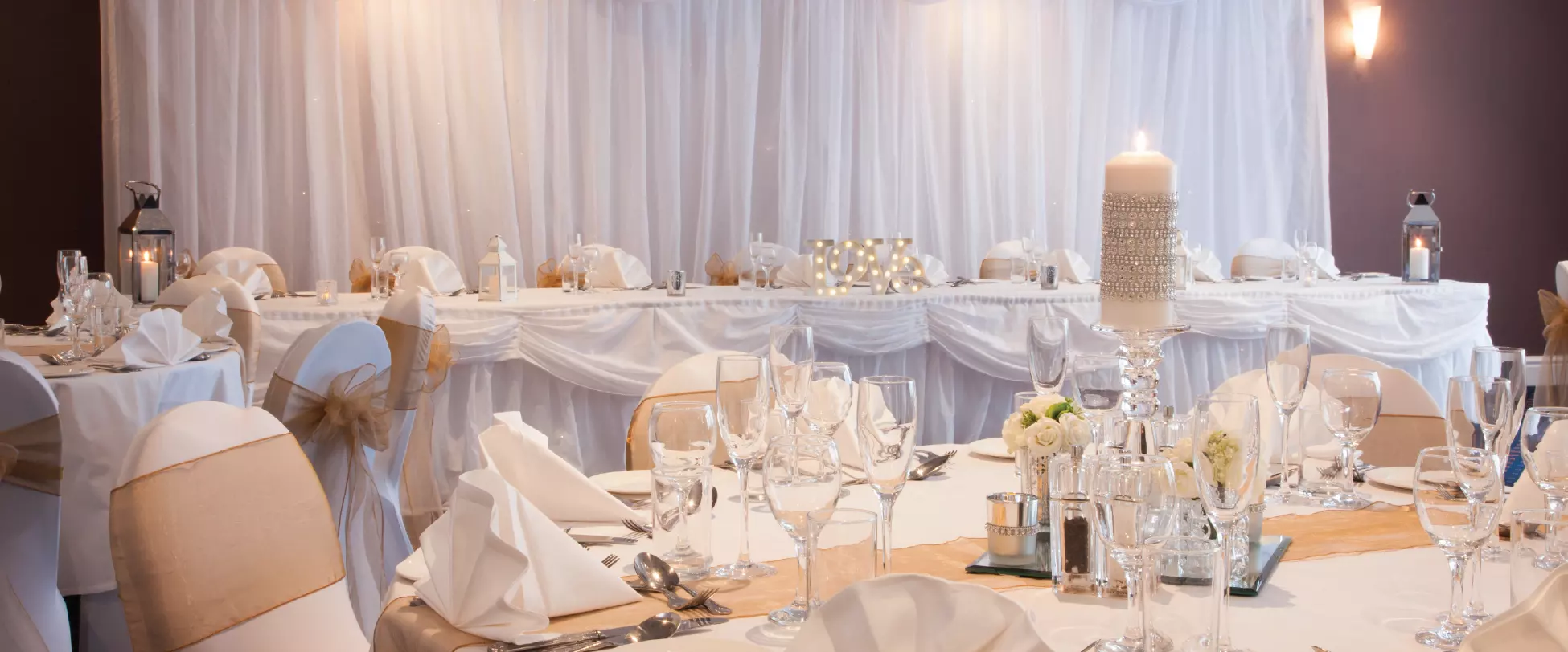 A wedding table set up with glassware, flowers and candles.